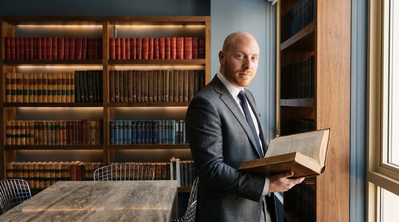 Samuel Bissu revisando un tomo en la biblioteca juridica del despacho